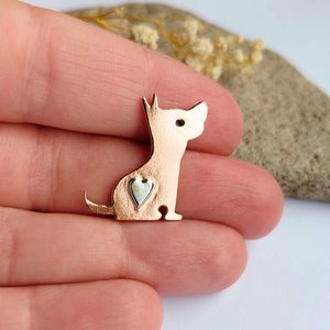 Copper dog brooch shown in a hand to illustrate its size