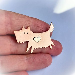 Copper scruffy terrier dog brooch shown in a hand to illustrate its size