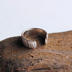 Close-up of handmade sterling silver ear cuff showing its detailed hammered texture