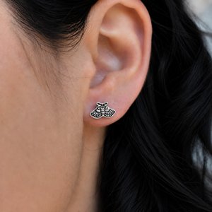 Sterling silver moth stud earring worn on a woman's earlobe, showing the petite size and intricate detail