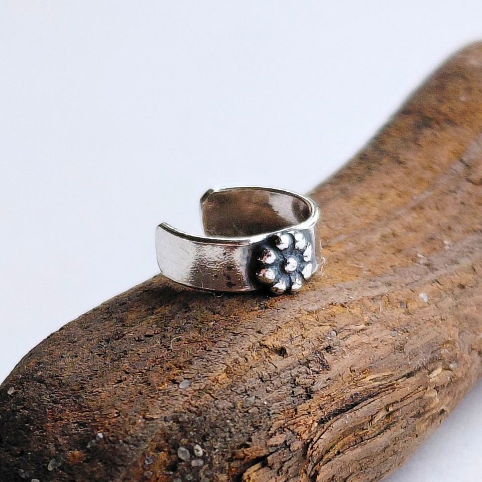 Sterling silver helix cuff with a textured fine silver daisy flower, shown from an angled view