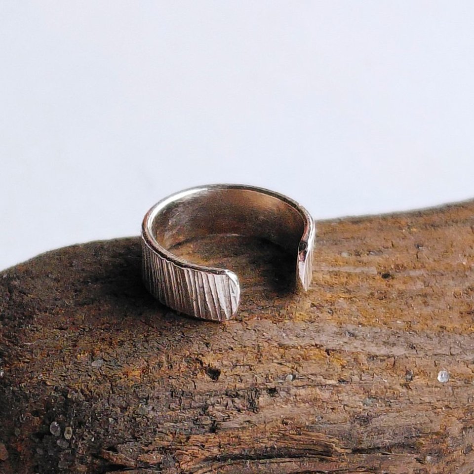 Close-up of handmade sterling silver ear cuff showing its detailed hammered texture